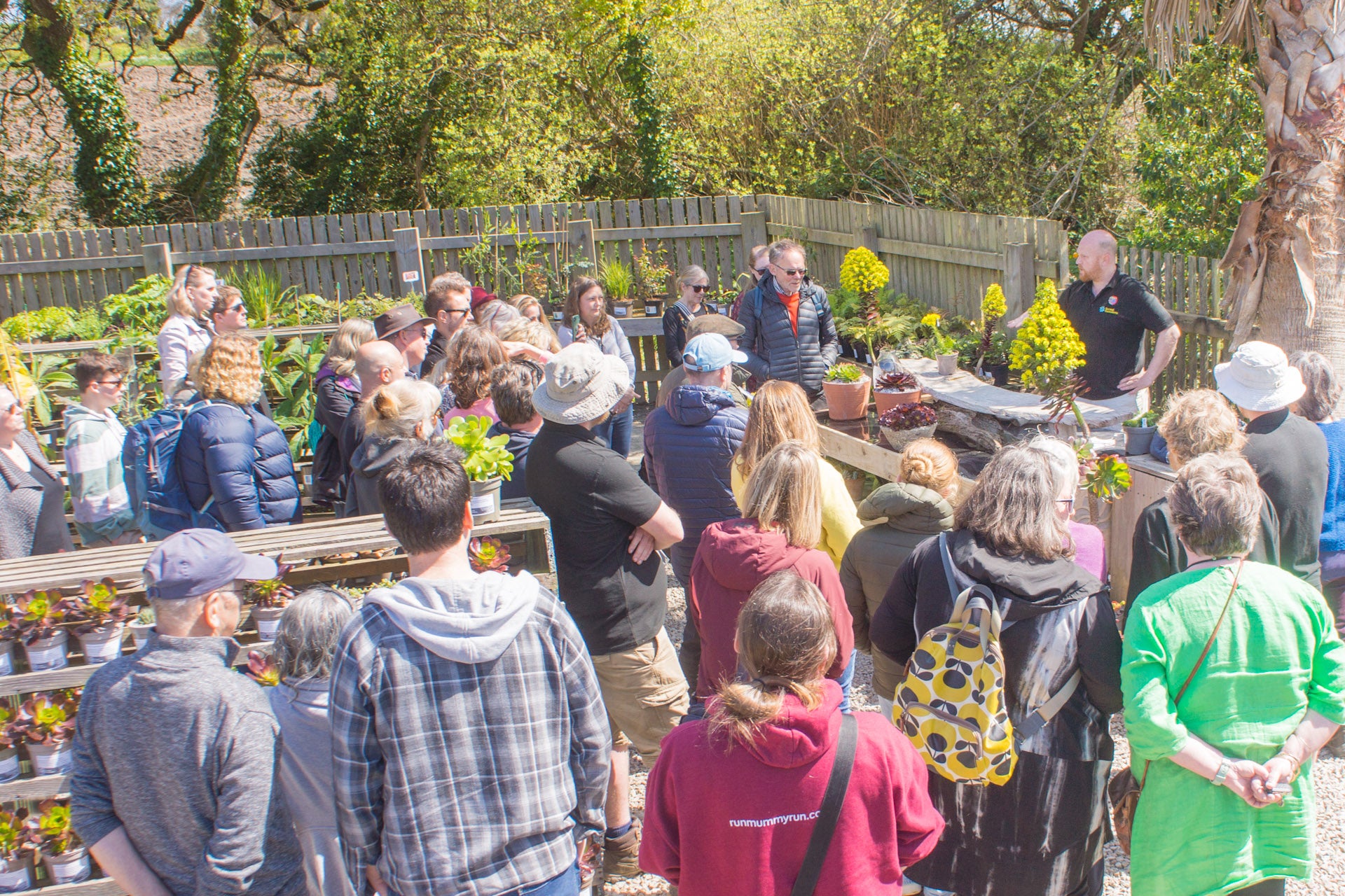 Group of people gathered around a table with plants in an outdoor setting